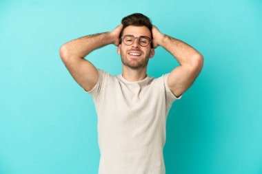 Genç beyaz yakışıklı adam mavi arka planda izole edilmiş gülüyor.