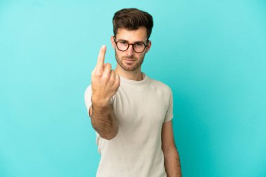 Beyaz tenli yakışıklı adam mavi arka planda izole edilmiş bir şekilde geliyor.