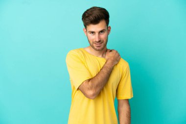 Genç beyaz yakışıklı adam mavi arka planda izole edilmiş gülüyor.