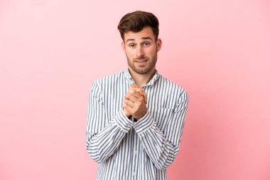 Beyaz tenli yakışıklı adam pembe arka planda izole edilmiş gülüyor.