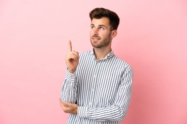 Pembe arka planda izole edilmiş beyaz, yakışıklı genç adam harika bir fikre işaret ediyor.