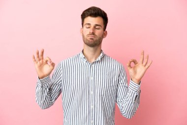 Zen pozisyonunda pembe arka planda izole edilmiş beyaz yakışıklı bir adam.