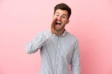 Pembe arka planda izole edilmiş, ağzı açık, bağıran beyaz, yakışıklı bir genç.