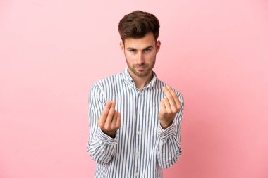 Beyaz tenli yakışıklı adam pembe arka planda izole edilmiş para hareketi yapıyor ama mahvolmuş.
