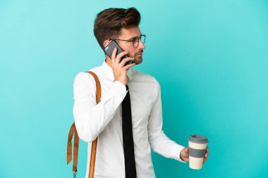 İş adamı izole edilmiş arka planda kahve ve cep telefonu tutuyor.