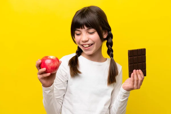 Malá Běloška Izolované Žlutém Pozadí Čokoládovou Tabletu Jedné Ruce Jablko — Stock fotografie