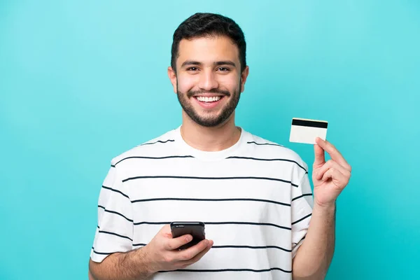 Mladý Brazilský Muž Izolované Modrém Pozadí Nákup Mobilem Kreditní Kartou — Stock fotografie