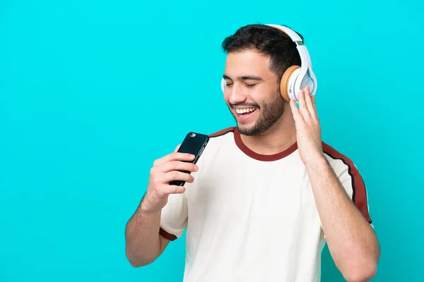 Νεαρός Βραζιλιάνος Απομονωμένος Μπλε Φόντο Ακούγοντας Μουσική Κινητό Και Τραγουδώντας — Φωτογραφία Αρχείου