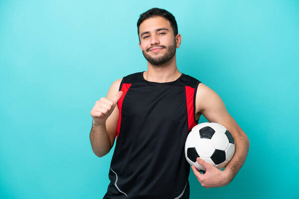 Young football player Brazilian man isolated on blue background proud and self-satisfied