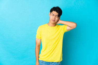 Mavi arka planda boynu ağrıyan genç bir Çinli.