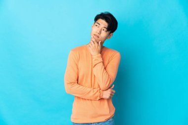 Mavi arka planda mahsur kalmış genç Çinli adamın şüpheleri var.