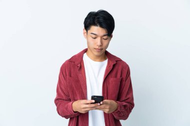 Genç Çinli adam beyaz arka planda cep telefonu kullanarak izole edilmiş.