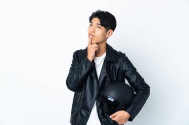 Motosiklet kasklı Çinli bir adam beyaz arka planda izole edilmiş ve yukarı bakarken şüpheleri var.