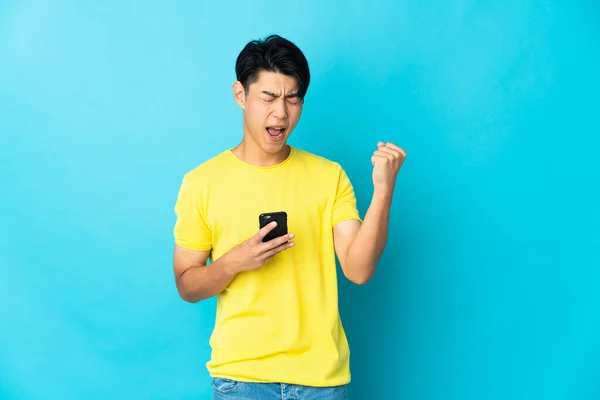 Young Chinese Man Isolated Blue Background Phone Victory Position — Stock Photo, Image