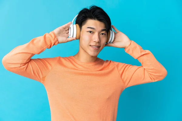 Jovem Chinês Isolado Fundo Azul Ouvindo Música — Fotografia de Stock