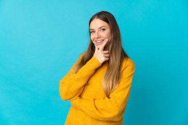 Genç Litvanyalı kadın mavi arka planda izole edilmiş mutlu ve gülümsüyor.