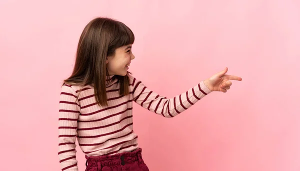 Malá Dívka Izolované Růžovém Pozadí Ukazující Prstem Stranu Prezentující Produkt — Stock fotografie