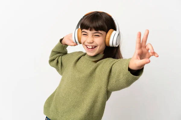小さな女の子リッスン音楽とともにモバイル隔離されたオンホワイトバックリスニング音楽と歌 — ストック写真