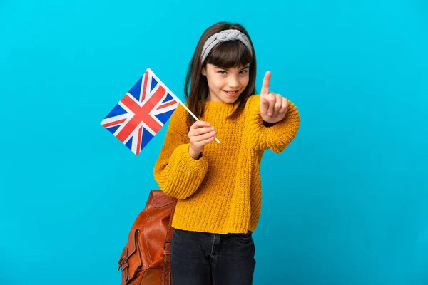 在蓝色背景下学习英语的小女孩露出并举起了一个手指 — 图库照片