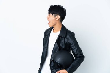 Motosiklet kasklı Çinli bir adam beyaz arka planda izole edilmiş. Yan pozisyonda gülüyor.