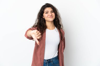 Beyaz arka planda izole edilmiş genç bir Rus kızı, olumsuz ifadeyle baş parmağını aşağı gösteriyor.