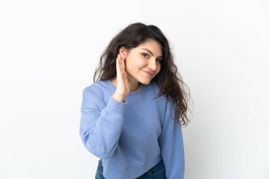 Genç Rus kız, beyaz arka planda izole edilmiş bir şekilde elini kulağına koyarak bir şeyler dinliyor.