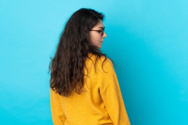 Genç Rus kız mavi arka planda izole edilmiş. Arka planda ve yan tarafta.