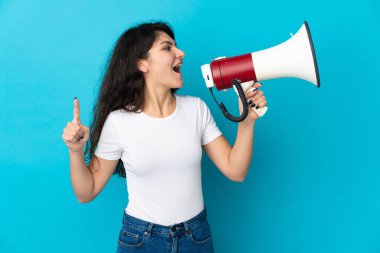 Genç Rus kız, mavi arka planda izole edilmiş bir şekilde megafonla bir şey duyurmak için bağırıyor.