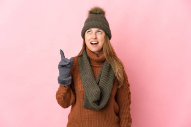 Kış şapkalı orta yaşlı bir kadın pembe arka planda izole edilmiş.