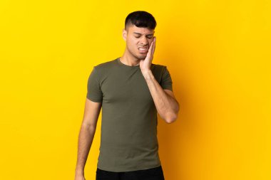 Sarı arka planda diş ağrısı olan genç bir Kolombiyalı izole edilmiş.
