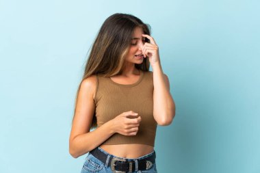 Mavi arka planda izole edilmiş genç beyaz kadın gülüyor.