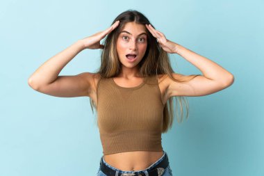 Mavi arka planda, sürpriz bir ifadeyle izole edilmiş beyaz bir kadın.