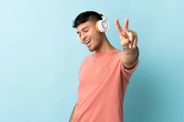 Молодий Колумбійський Чоловік Ізольований Синьому Фоні Слухає Музику Співає — стокове фото