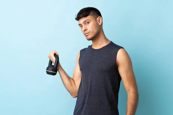 Young Colombian Man Isolated Blue Background Making Weightlifting Kettlebell — Stock Photo, Image