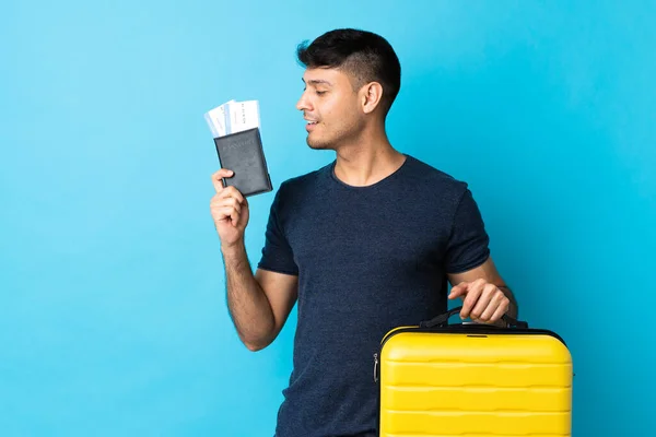 Jonge Colombiaanse Man Geïsoleerd Blauwe Achtergrond Vakantie Met Koffer Paspoort — Stockfoto