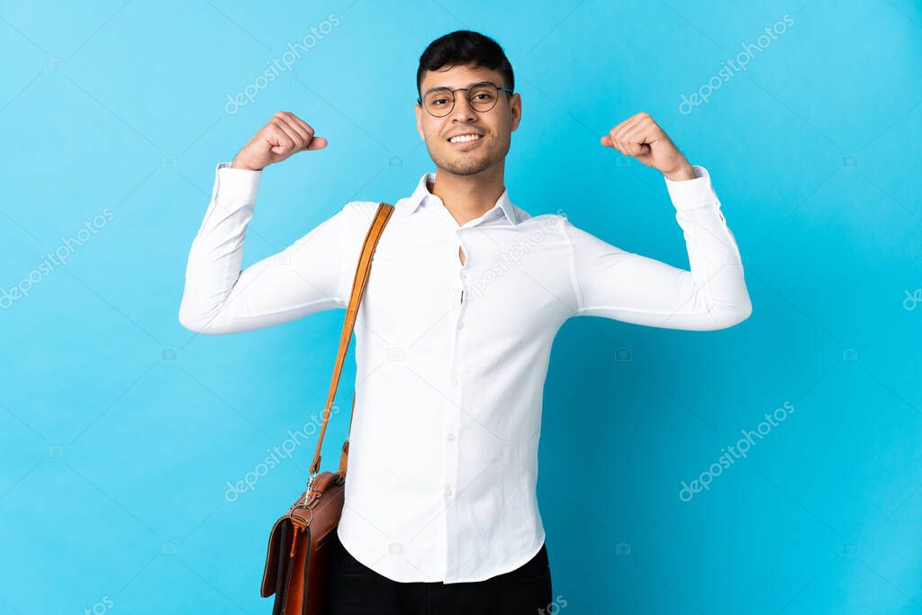 Young business Colombian man isolated on blue background doing strong gesture