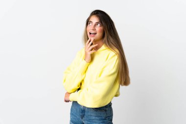 Beyaz arka planda izole edilmiş genç beyaz kadın gülümserken yukarı bakıyor.