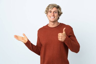 İzole edilmiş beyaz arkaplan üzerindeki İngiliz adam bir reklam vermek ve başparmaklarını kaldırarak avucunun içinde sanal bir alan tutuyor.