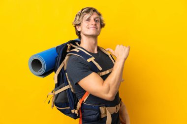 Genç dağcı sarı arka planda gururlu ve kendini beğenmiş.