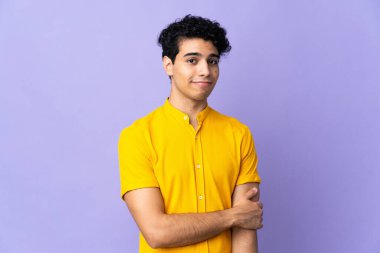 Genç Venezuelalı adam, mor arka planda izole edilmiş gülüyor.