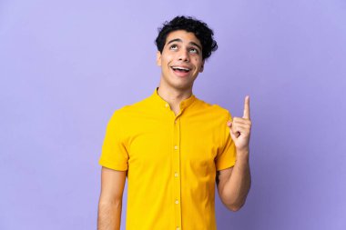 Genç Venezuelalı adam mor arka planda izole edilmiş yukarı bakıyor ve şaşırıyor