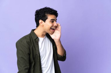 Genç Venezuelalı bir adam mor arka planda izole edilmiş ve ağzı açık bağırıyor.