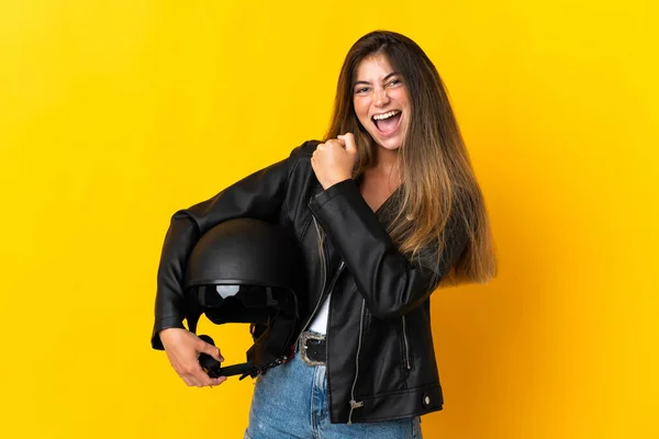 勝利を祝う黄色の背景に隔離されたオートバイのヘルメットを持っている女性 — ストック写真