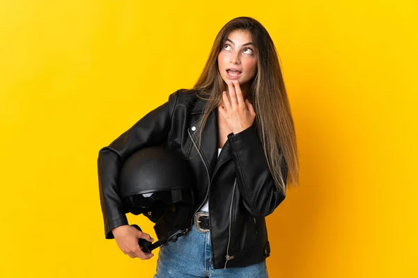 女性保持Aオートバイヘルメット隔離上の黄色の背景上を見ながら笑顔 — ストック写真