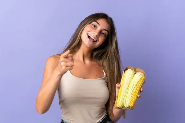 Jovem Segurando Milho Isolado Fundo Roxo Aponta Dedo Para Você — Fotografia de Stock