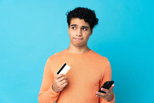 Venezuelai Férfi Elszigetelt Kék Háttér Vásárol Mobil Egy Hitelkártya Miközben — Stock Fotó