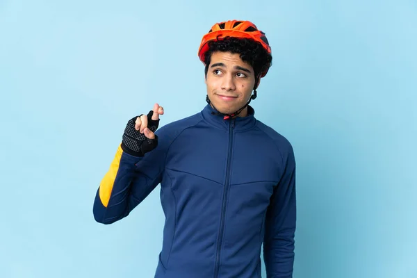 Hombre Ciclista Venezolano Aislado Sobre Fondo Azul Con Dedos Cruzando — Foto de Stock
