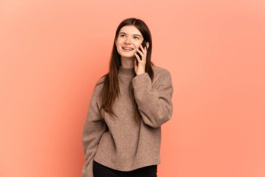 Pembe arka planda izole edilmiş genç Ukraynalı bir kız cep telefonuyla sohbet ediyor.