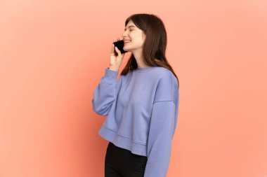 Pembe arka planda izole edilmiş genç Ukraynalı kız cep telefonuyla sohbet ediyor.