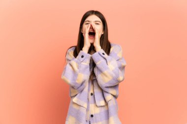 Pembe arka planda izole edilmiş genç Ukraynalı kız bağırıyor ve bir şeyler söylüyor.